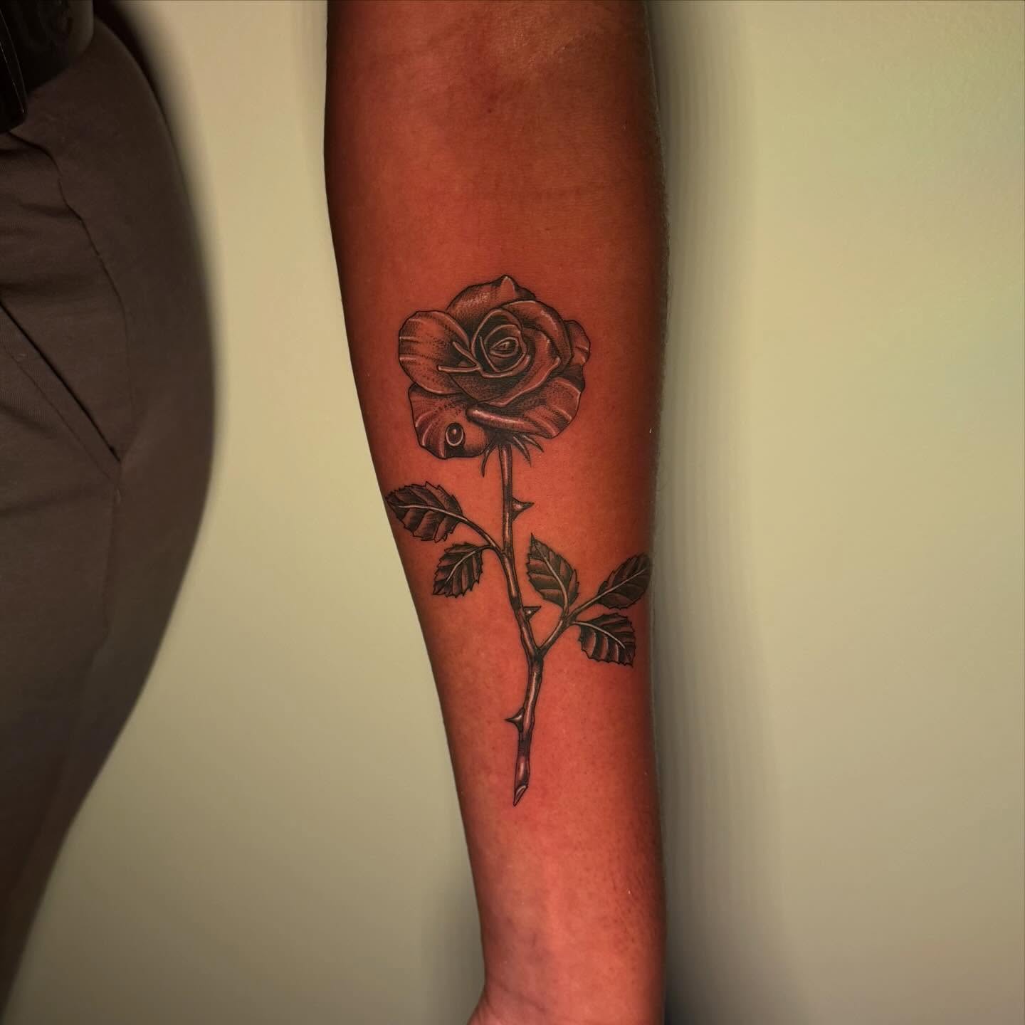 Meticulously shaded fine-line single stem rose forearm tattoo